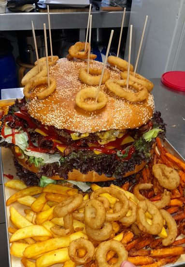 Big Dora — 8.667g Riesenburger mit Pommes und Zwiebelringen, Blick von oben auf das volle Tablett