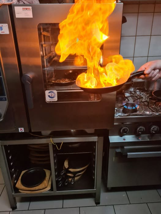 Flambierende Pfanne in der Schlossgewölbe Küche — frisch zubereitet mit offener Flamme