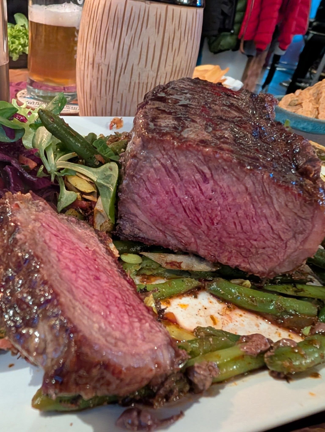 Perfekt medium-rare gegrilltes Steak mit grünen Bohnen und frischem Salat